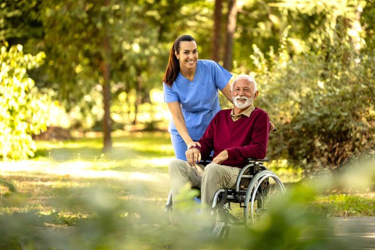 Older adults share a meal and conversation in a bright assisted living dining room.