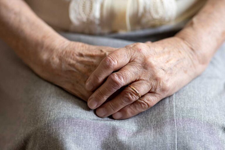 Older adult choosing clothing with a caregiver in a bright assisted living room.